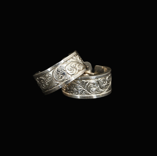 A pair of hand-crafted sterling silver huggies with intricate, hand-engraved acanthus leaves.