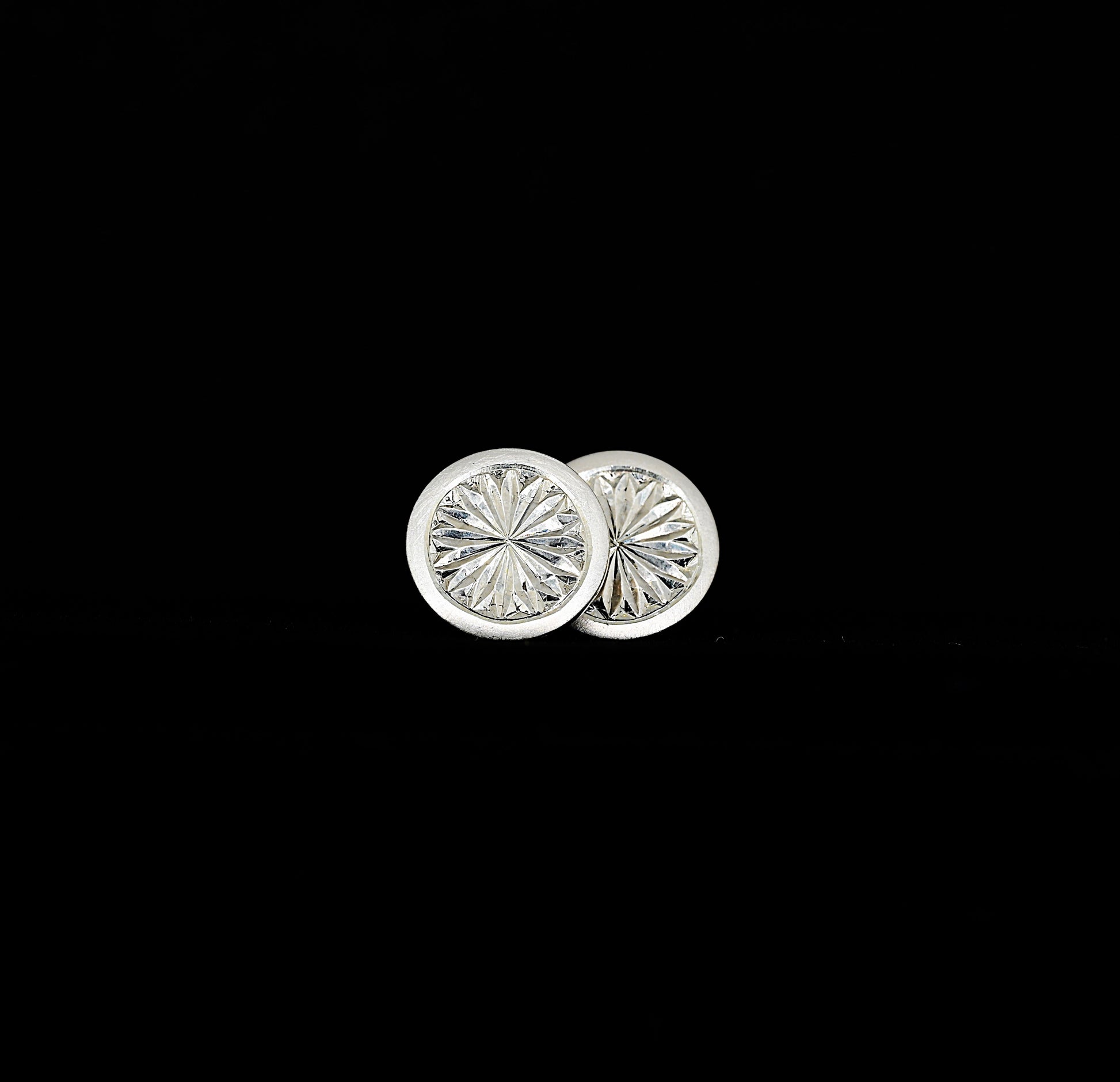 A pair of hand-engraved sterling silver stud earrings with a floral pattern