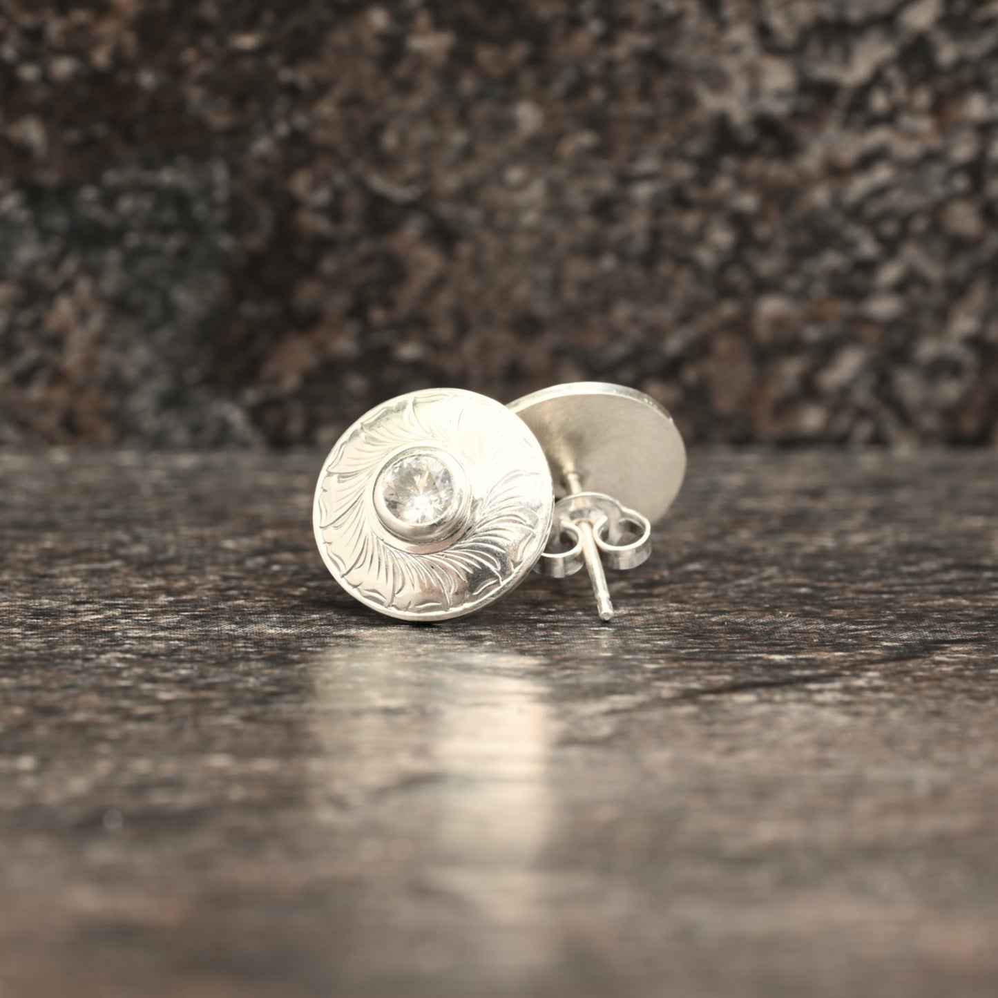 Sterling silver stud earrings with hand‑engraved leaf motif and white sapphire centre