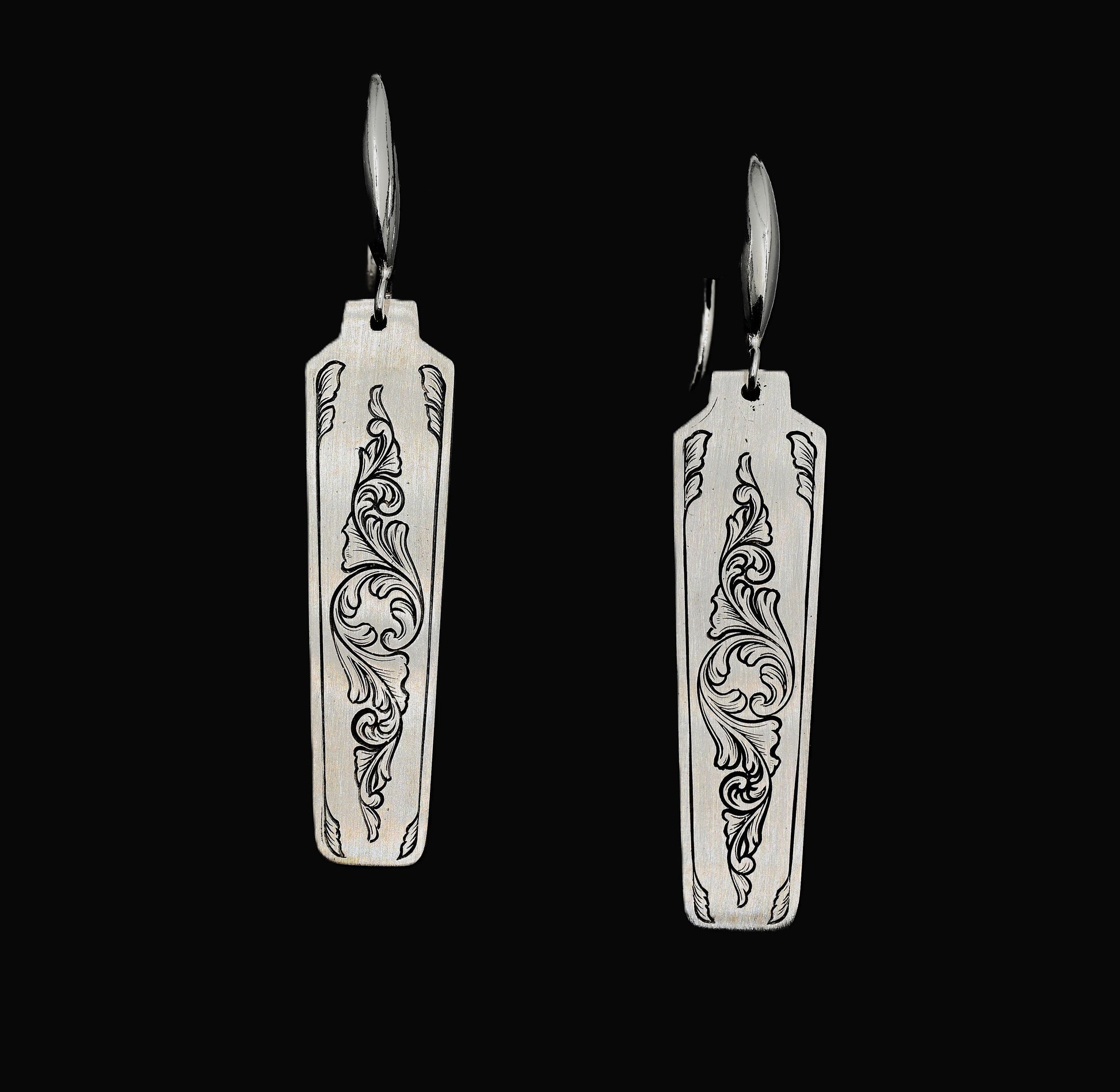 A pair of hand-crafted sterling silver statement earrings with hand-engraved acanthus patterns.