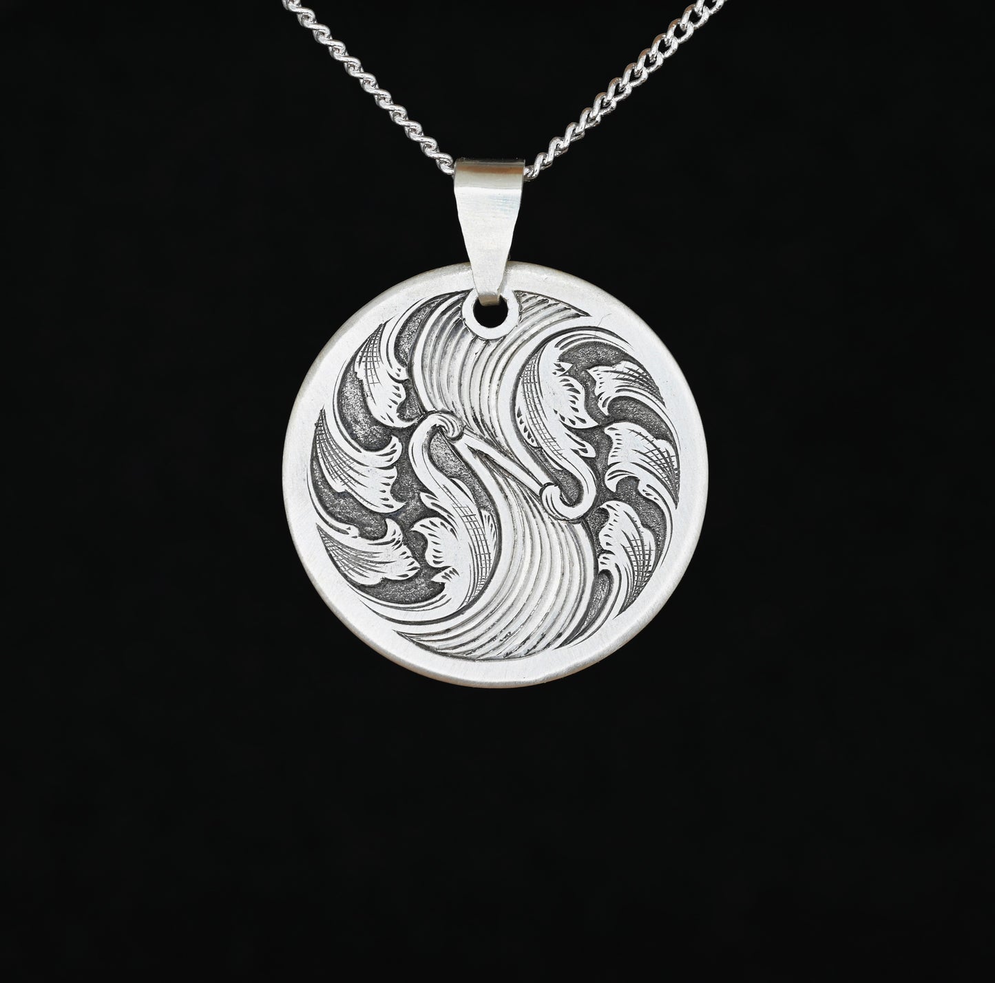 A sterling silver disc pendant with hand-crafted bale featuring an engraved acanthus wave design.