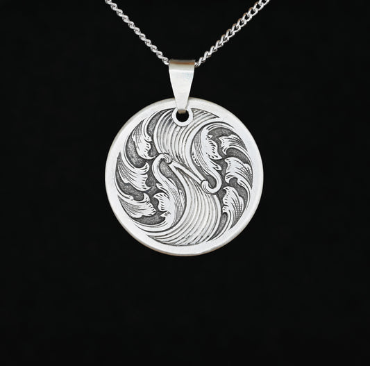 A sterling silver disc pendant with hand-crafted bale featuring an engraved acanthus wave design.