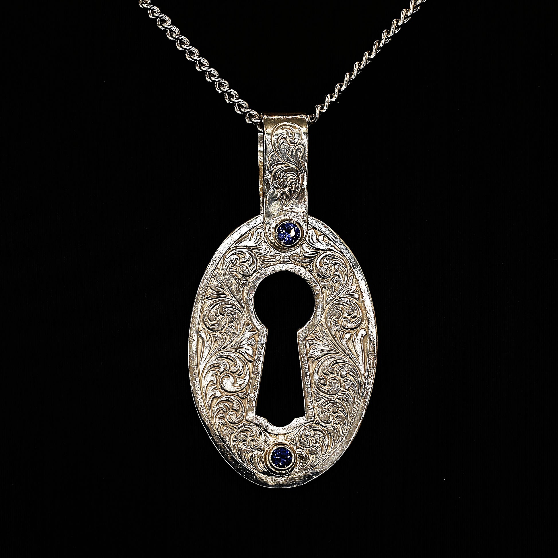 A sterling silver pendant with hand-engraved acanthus ceylon sapphires, in the shape of a lock