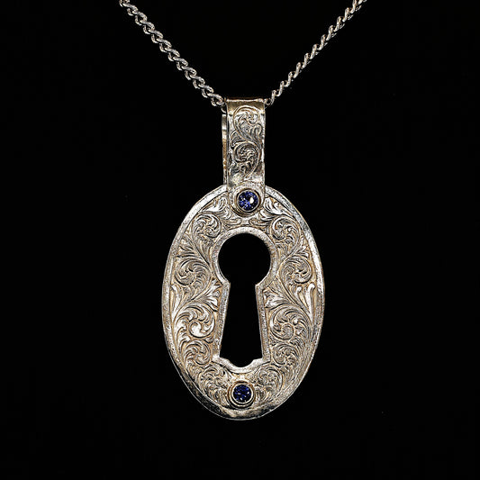 A sterling silver pendant with hand-engraved acanthus ceylon sapphires, in the shape of a lock