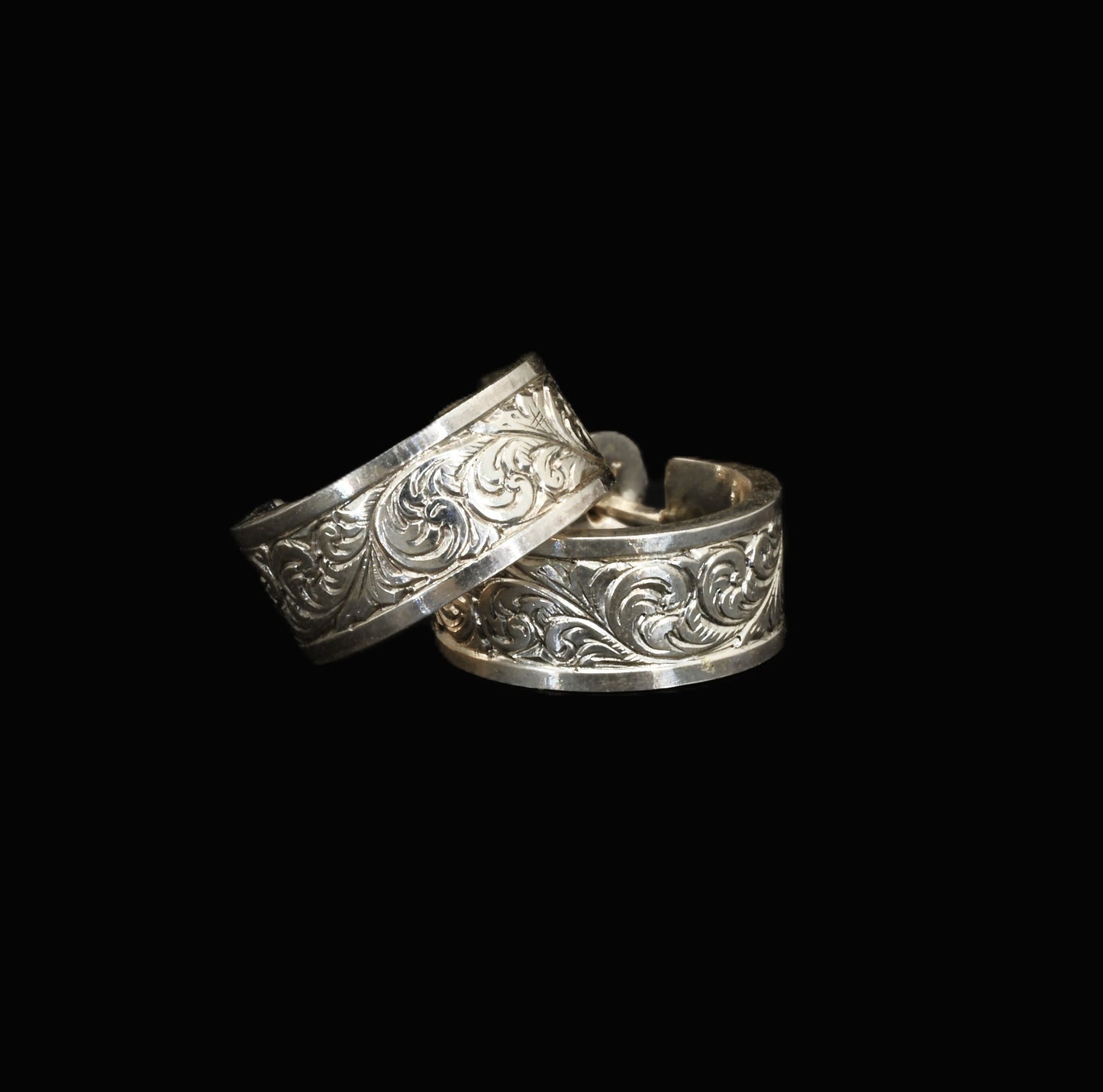 A pair of hand-crafted sterling silver huggies with intricate, hand-engraved acanthus leaves.