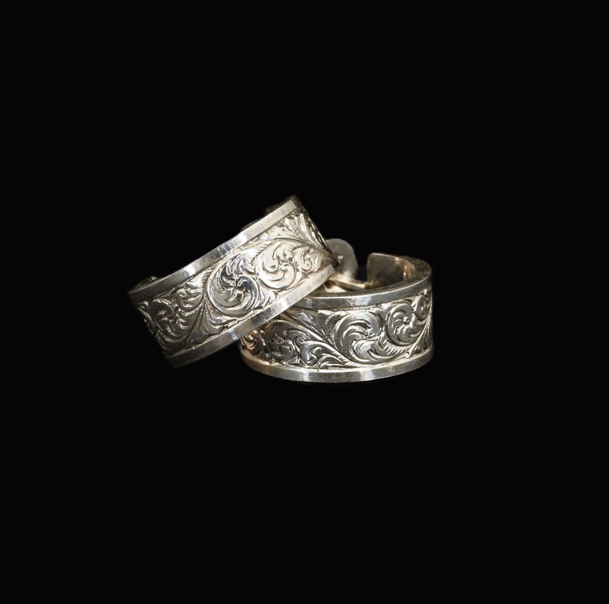 A pair of hand-crafted sterling silver huggies with intricate, hand-engraved acanthus leaves.