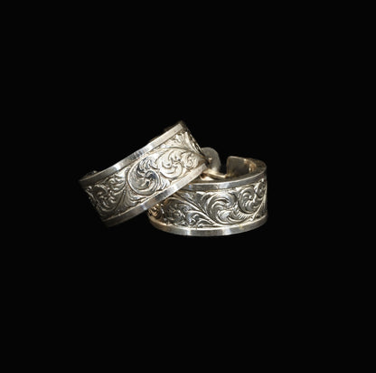 A pair of hand-crafted sterling silver huggies with intricate, hand-engraved acanthus leaves.