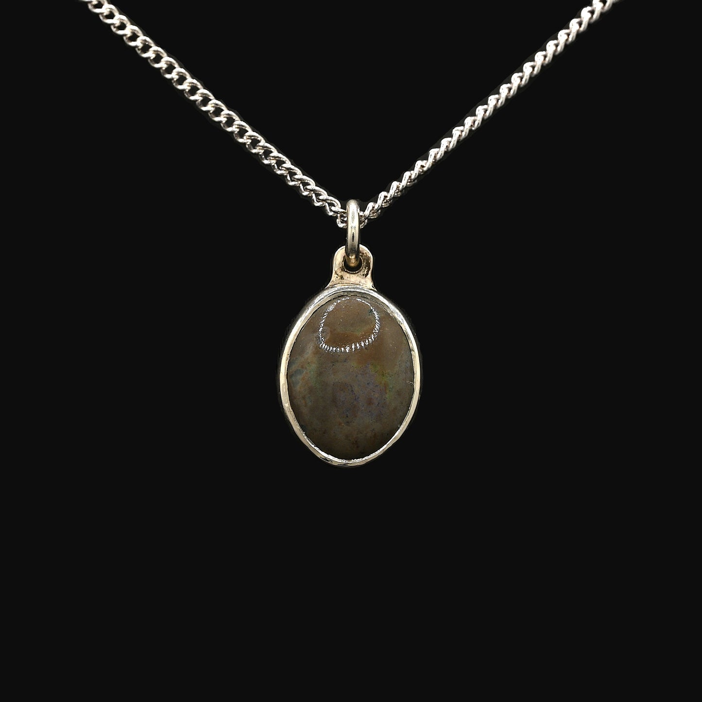 A silver pendant featuring an oval-shaped Andamooka opal with purple and green highlights