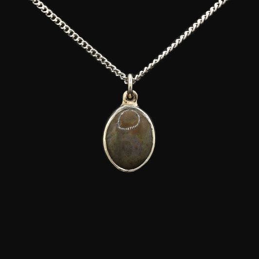 A silver pendant featuring an oval-shaped Andamooka opal with purple and green highlights