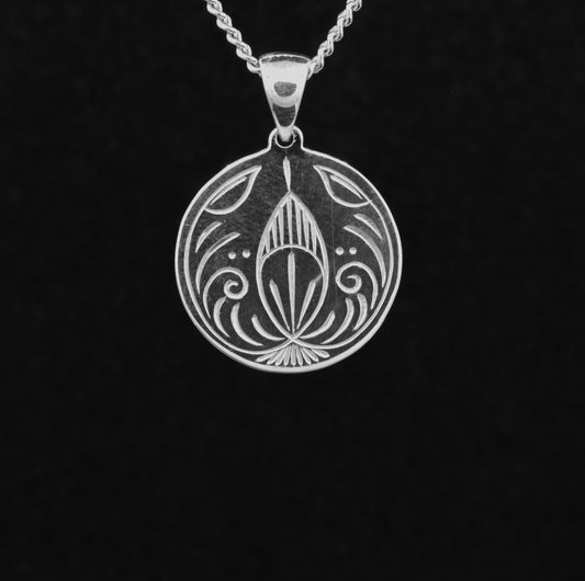 A sterling silver hand-engraved disc pendant with a Christmas bauble design
