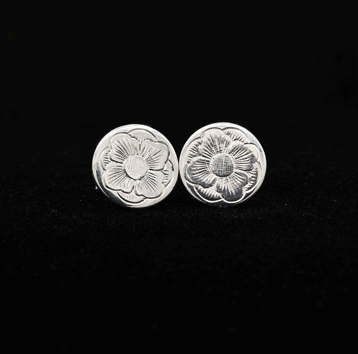 A pair of hand-engraved sterling silver stud earrings with a floral design