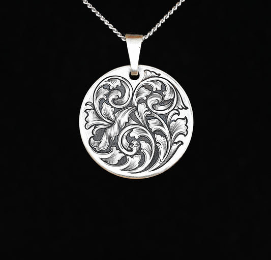 A sterling silver disc pendant with a hand-engraved acanthus vine design