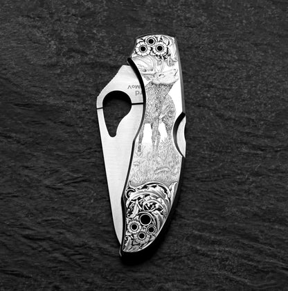A silver Spyderco knife with an image of a roaring stag and floral embellishments