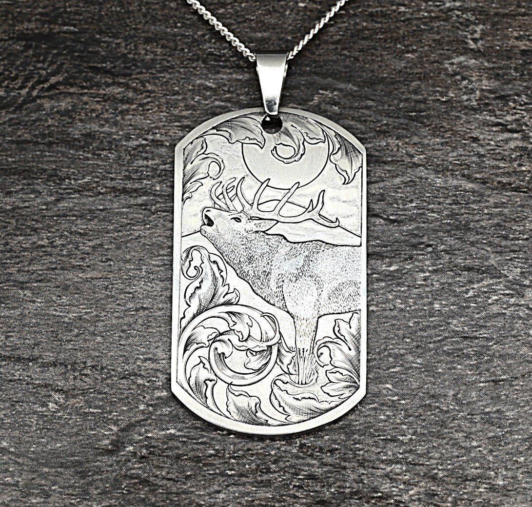 Hand-engraved titanium pendant with red deer calling in the moonlight, surrounded by traditional scrollwork