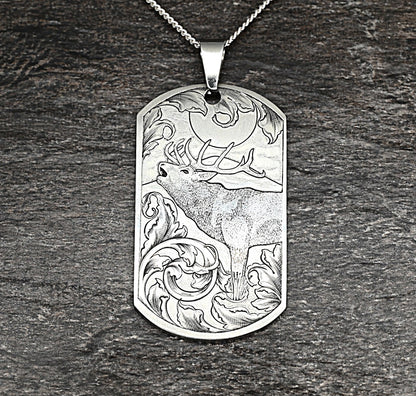 Hand-engraved titanium pendant with red deer calling in the moonlight, surrounded by traditional scrollwork