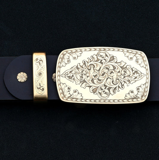 Hand‑engraved brass Western belt buckle set with acanthus scrollwork on dark leather.