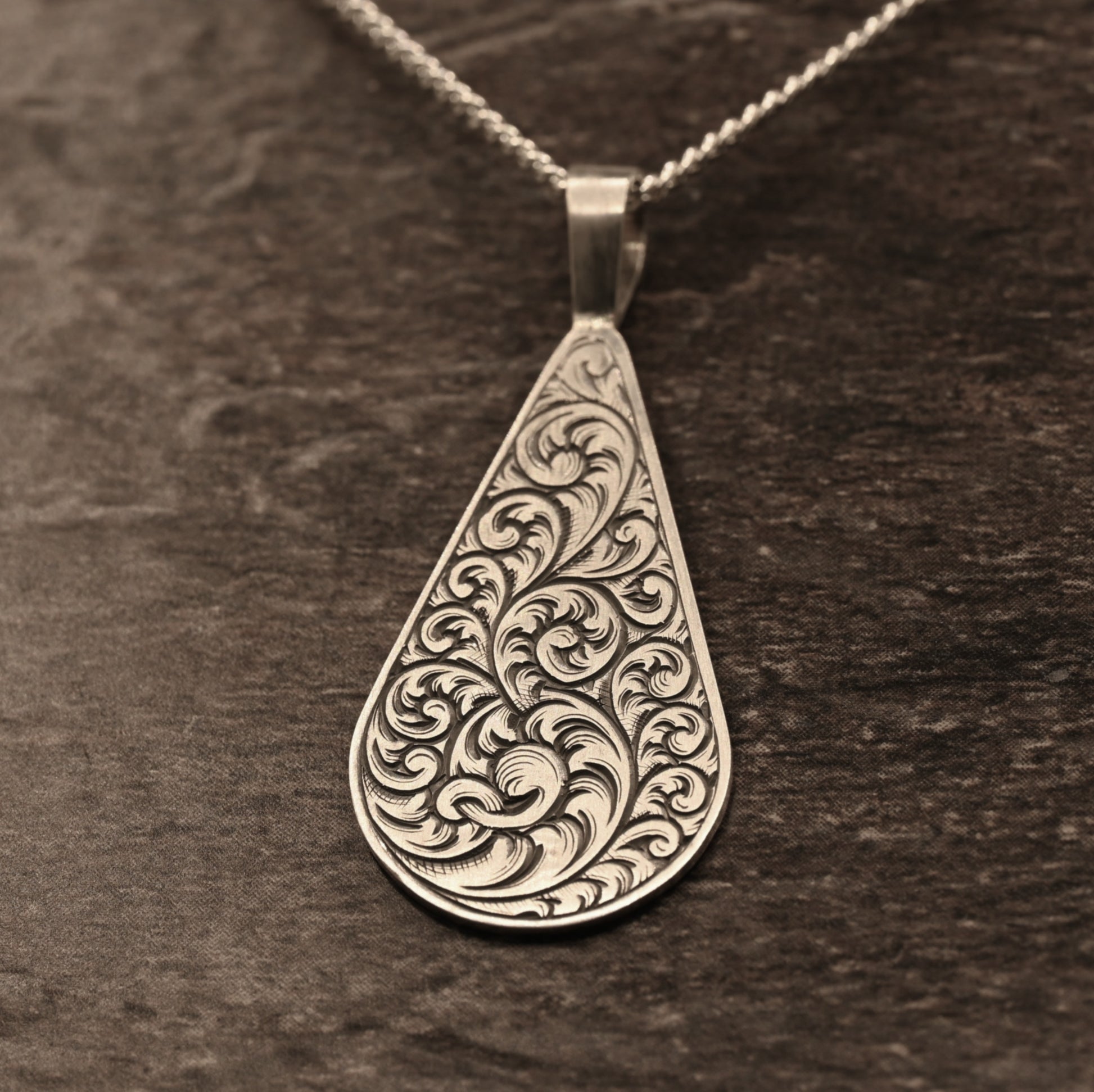 Hand-engraved sterling silver teardrop pendant with ornate scrollwork