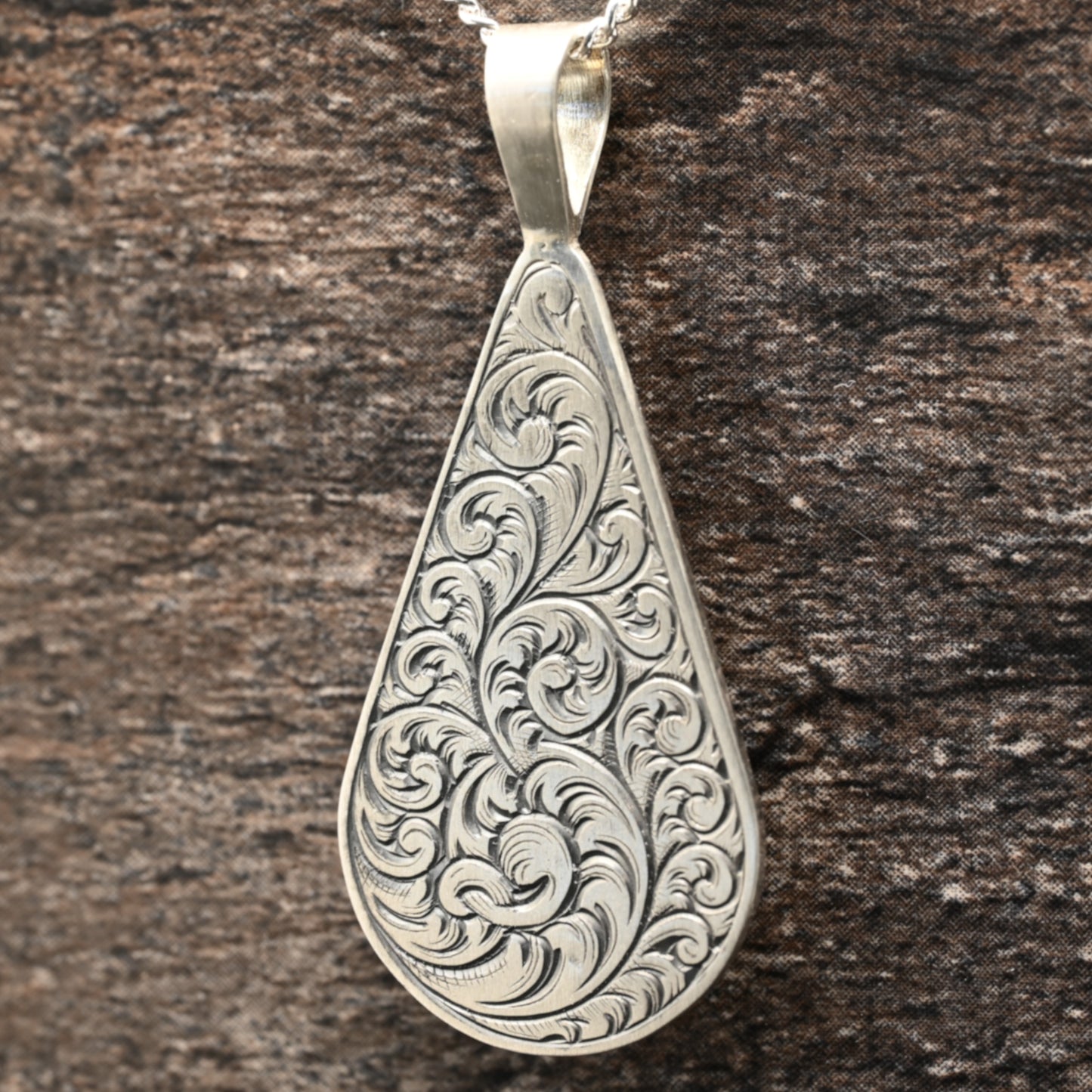 Hand-engraved sterling silver teardrop pendant with ornate scrollwork