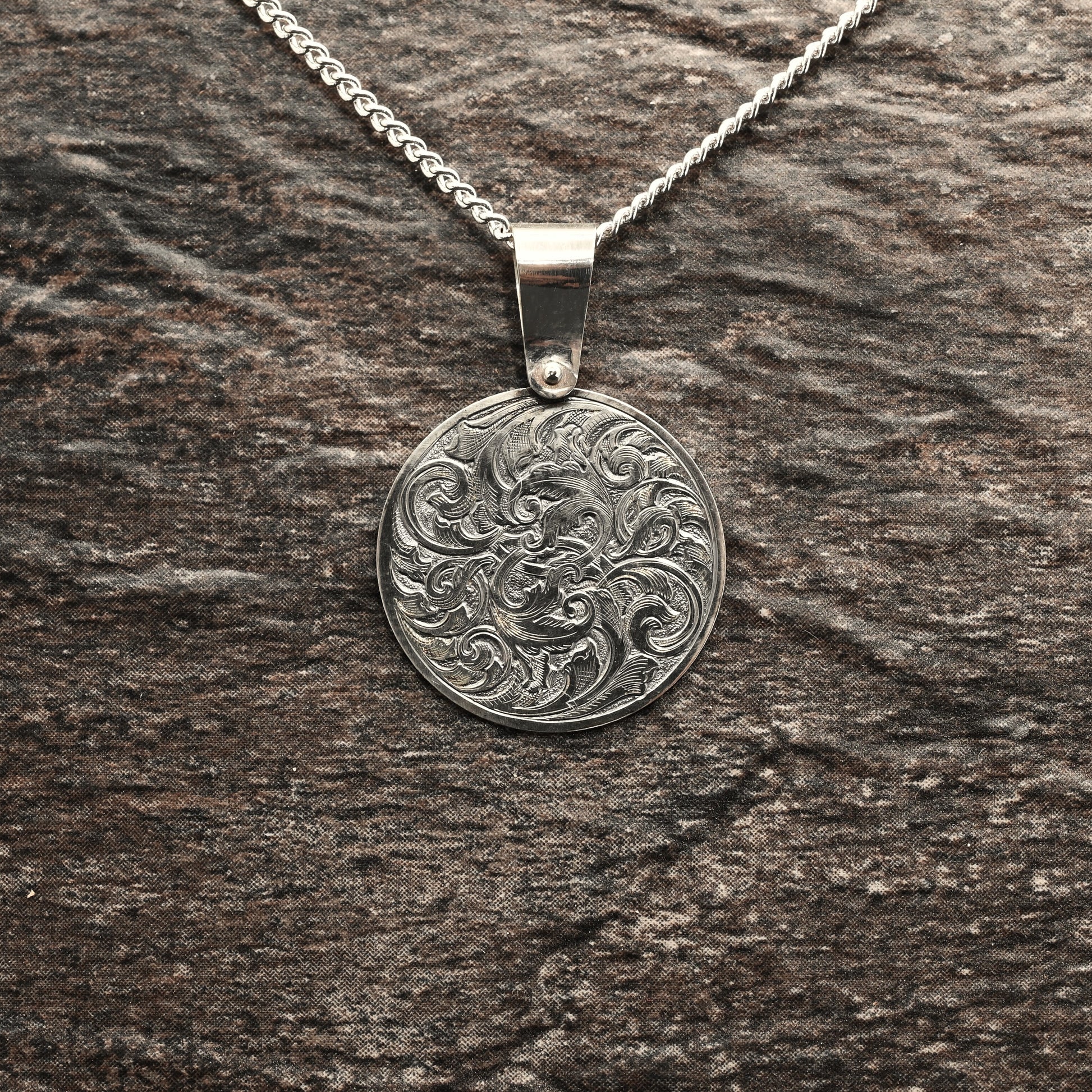 Hand-engraved round sterling silver pendant, featuring traditional acanthus design