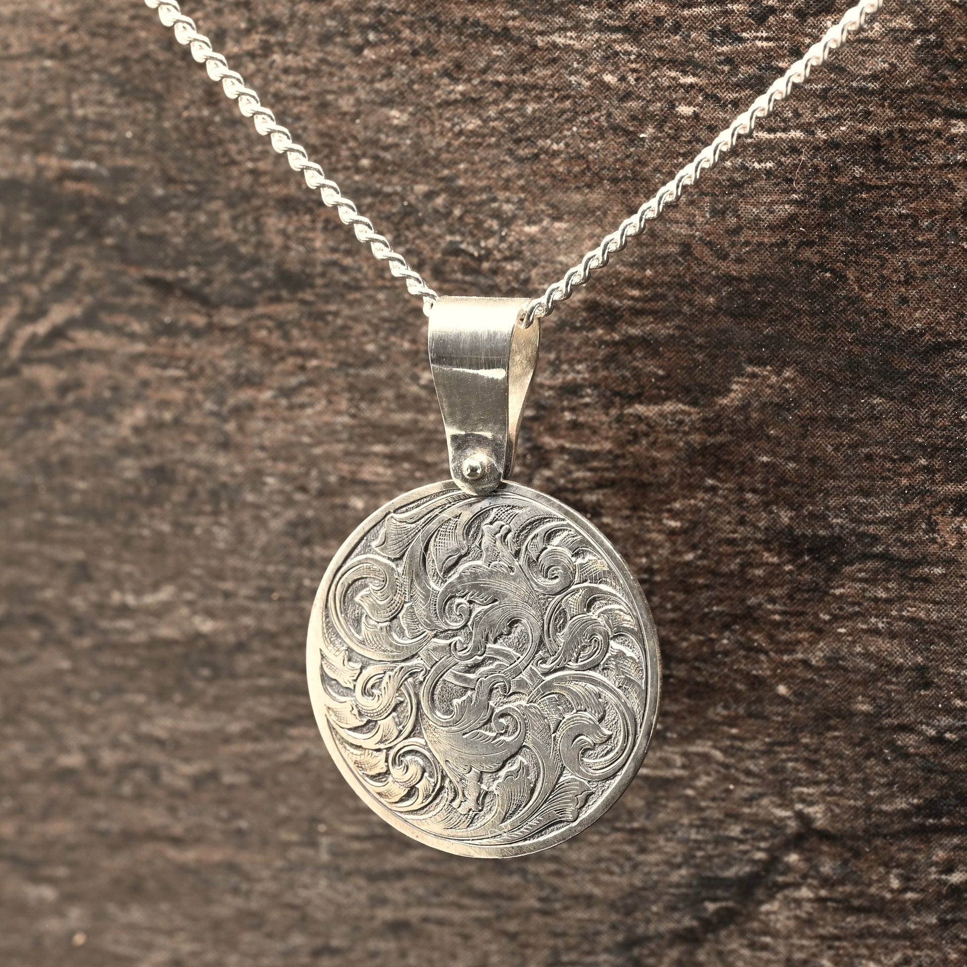 Hand-engraved round sterling silver pendant, featuring traditional acanthus design