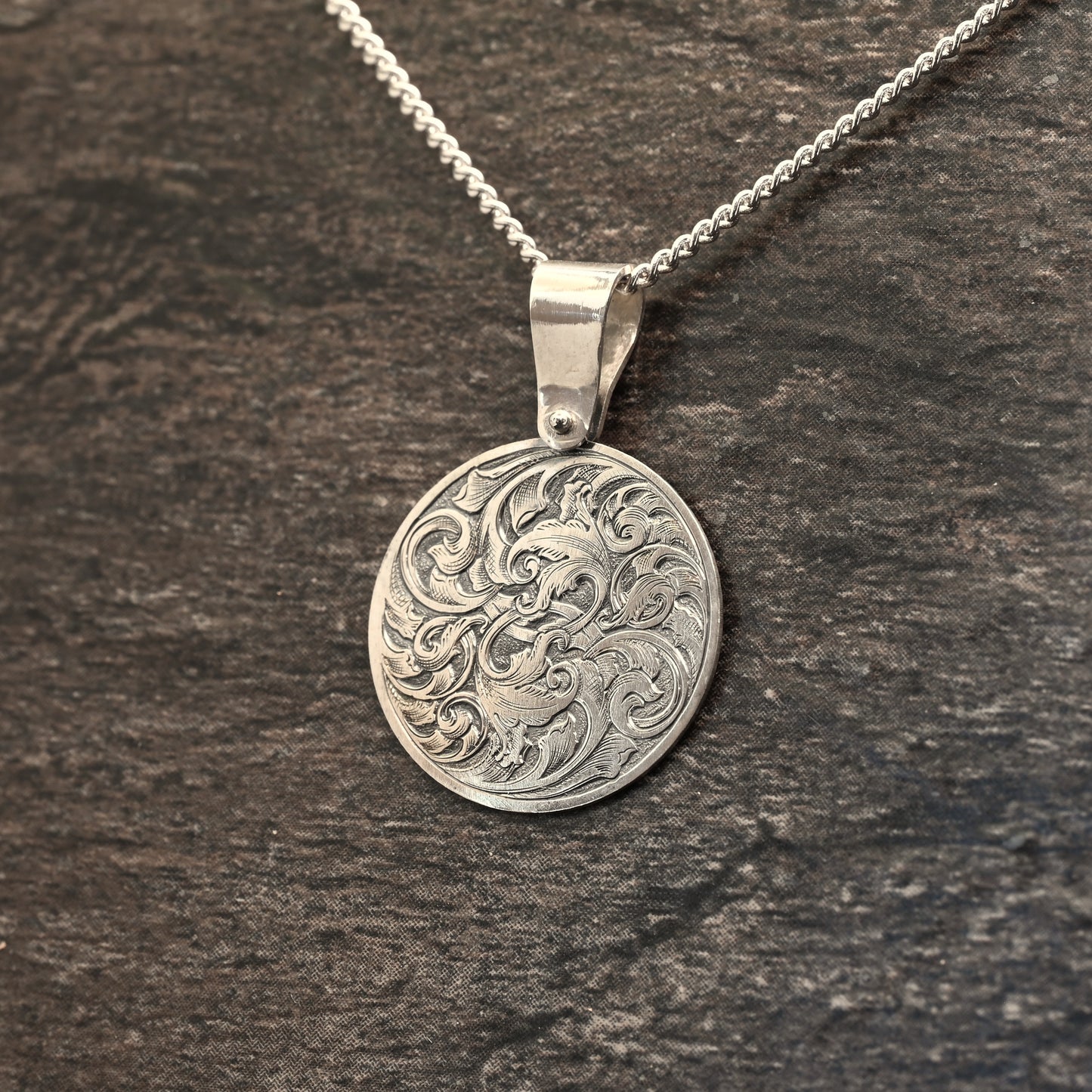 Hand-engraved round sterling silver pendant, featuring traditional acanthus design