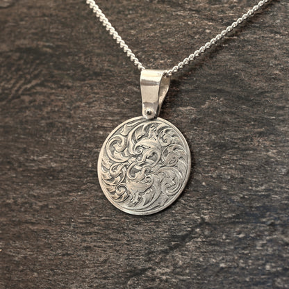 Hand-engraved round sterling silver pendant, featuring traditional acanthus design