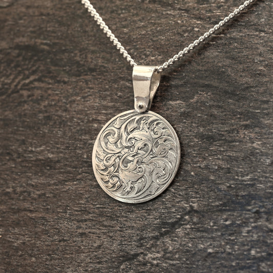 Hand-engraved round sterling silver pendant, featuring traditional acanthus design