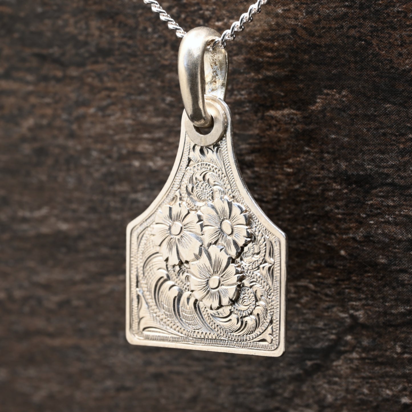 Sterling silver cattle-tag pendant with hand‑engraved scroll and floral design