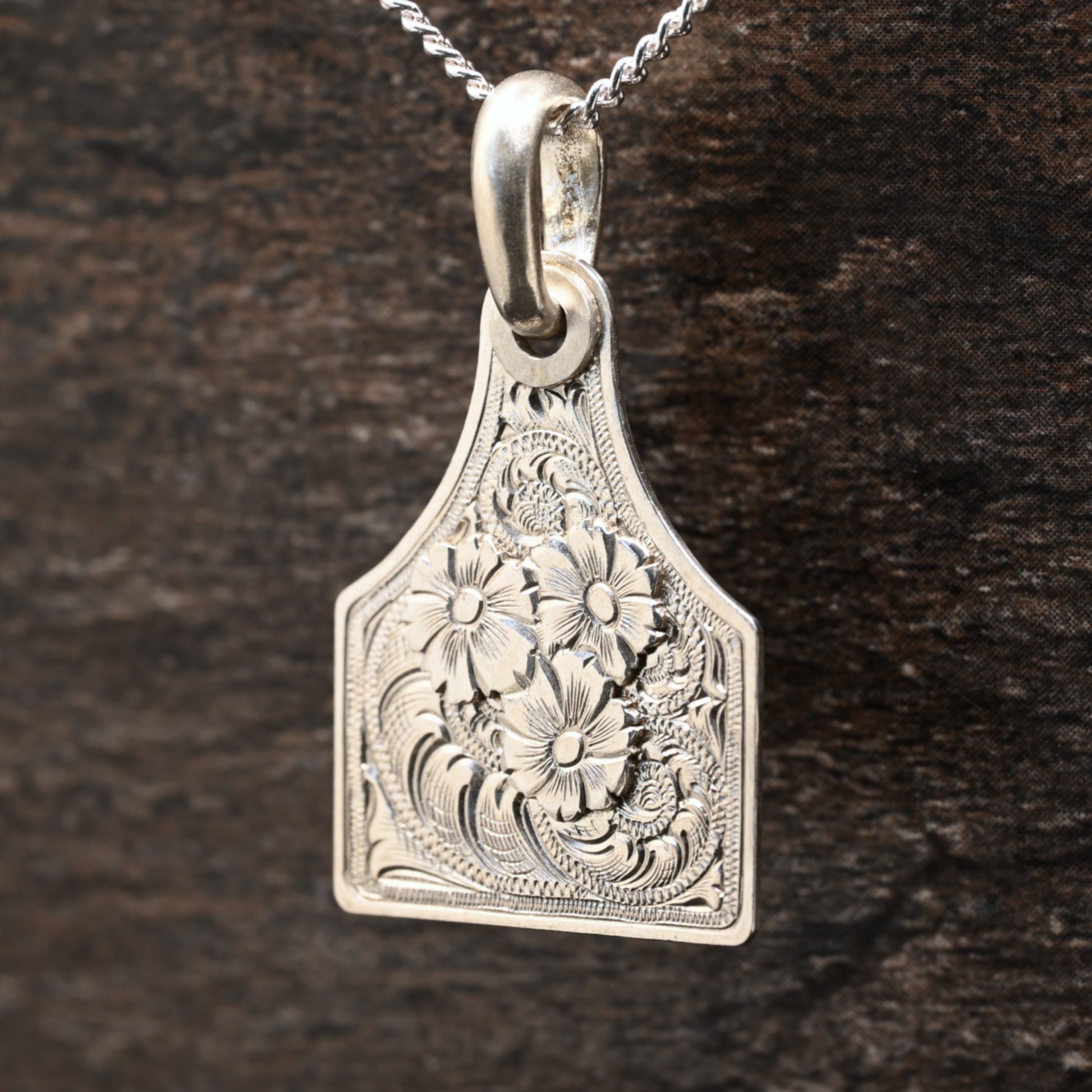Sterling silver cattle-tag pendant with hand‑engraved scroll and floral design