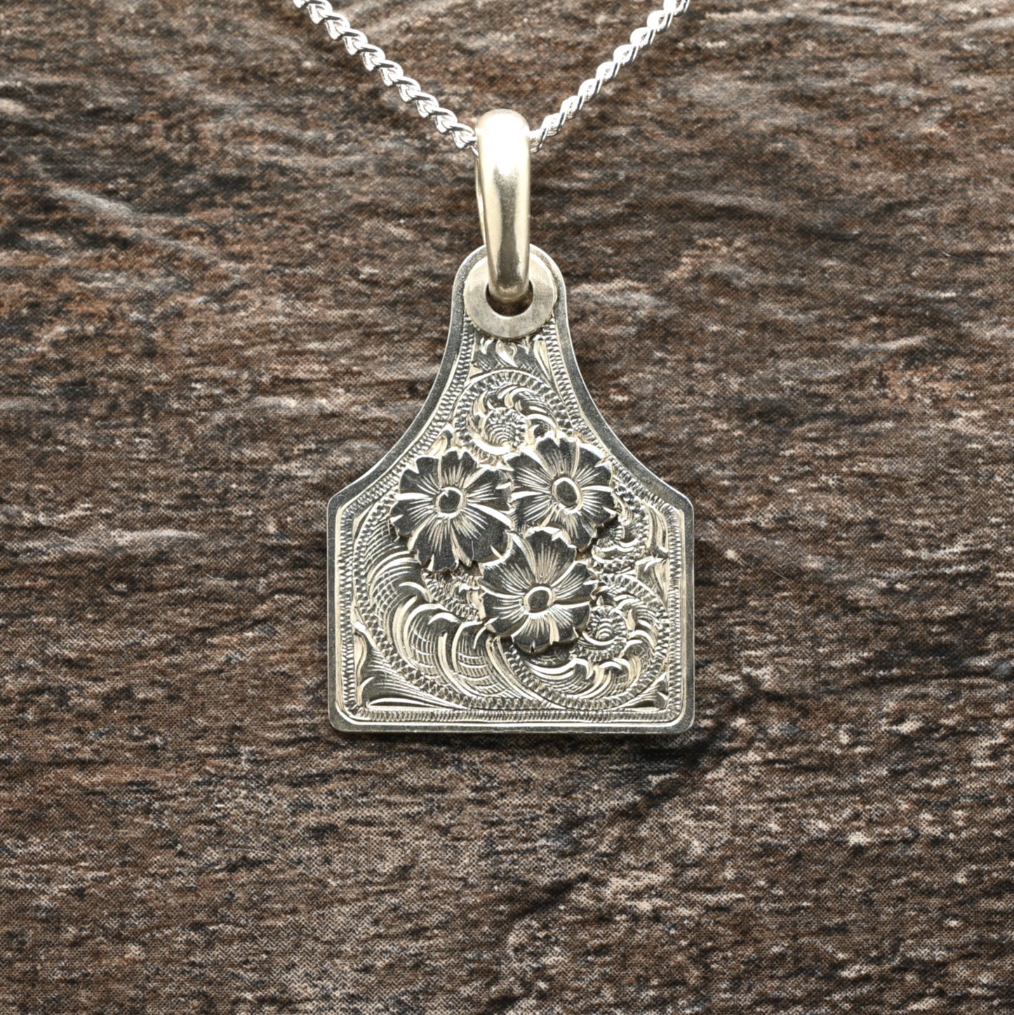 Sterling silver cattle-tag pendant with hand‑engraved scroll and floral design