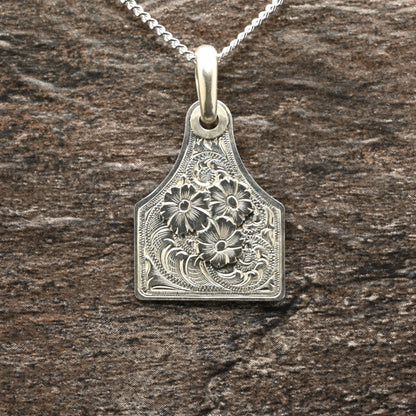 Sterling silver cattle-tag pendant with hand‑engraved scroll and floral design