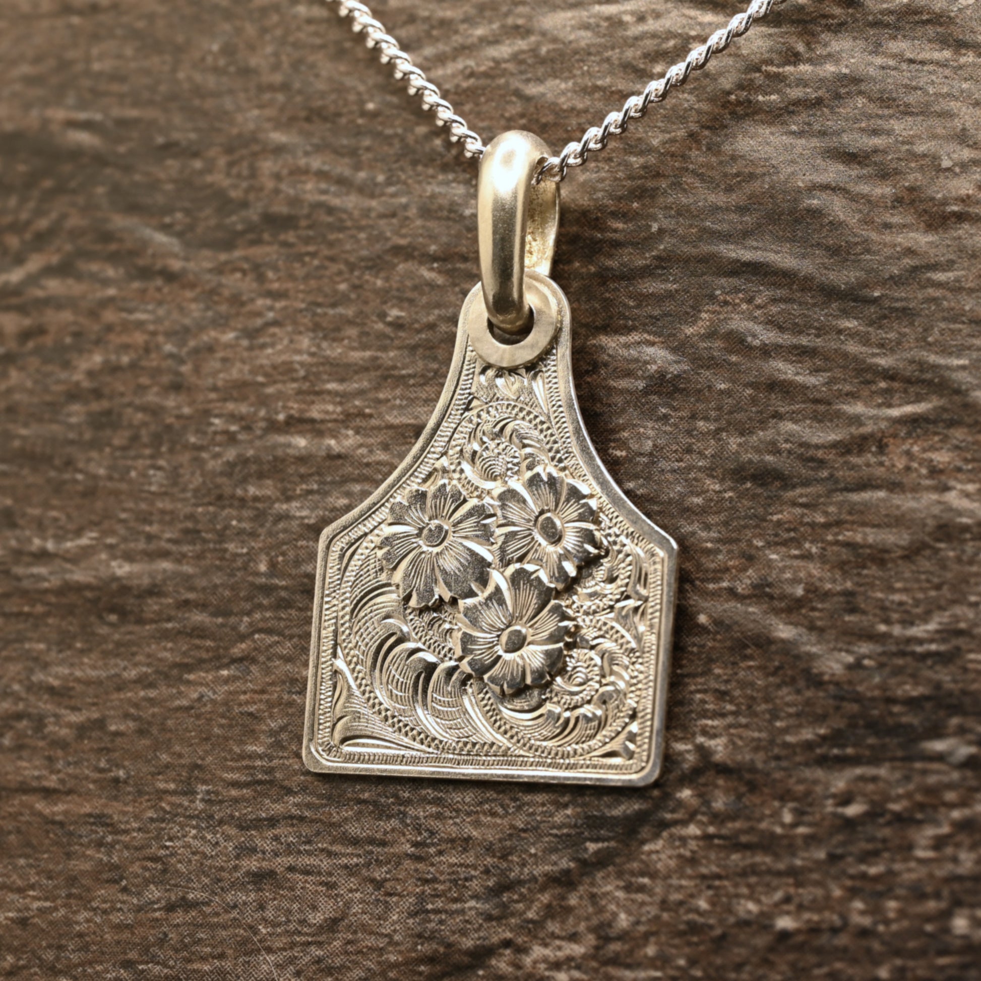 Sterling silver cattle-tag pendant with hand‑engraved scroll and floral design
