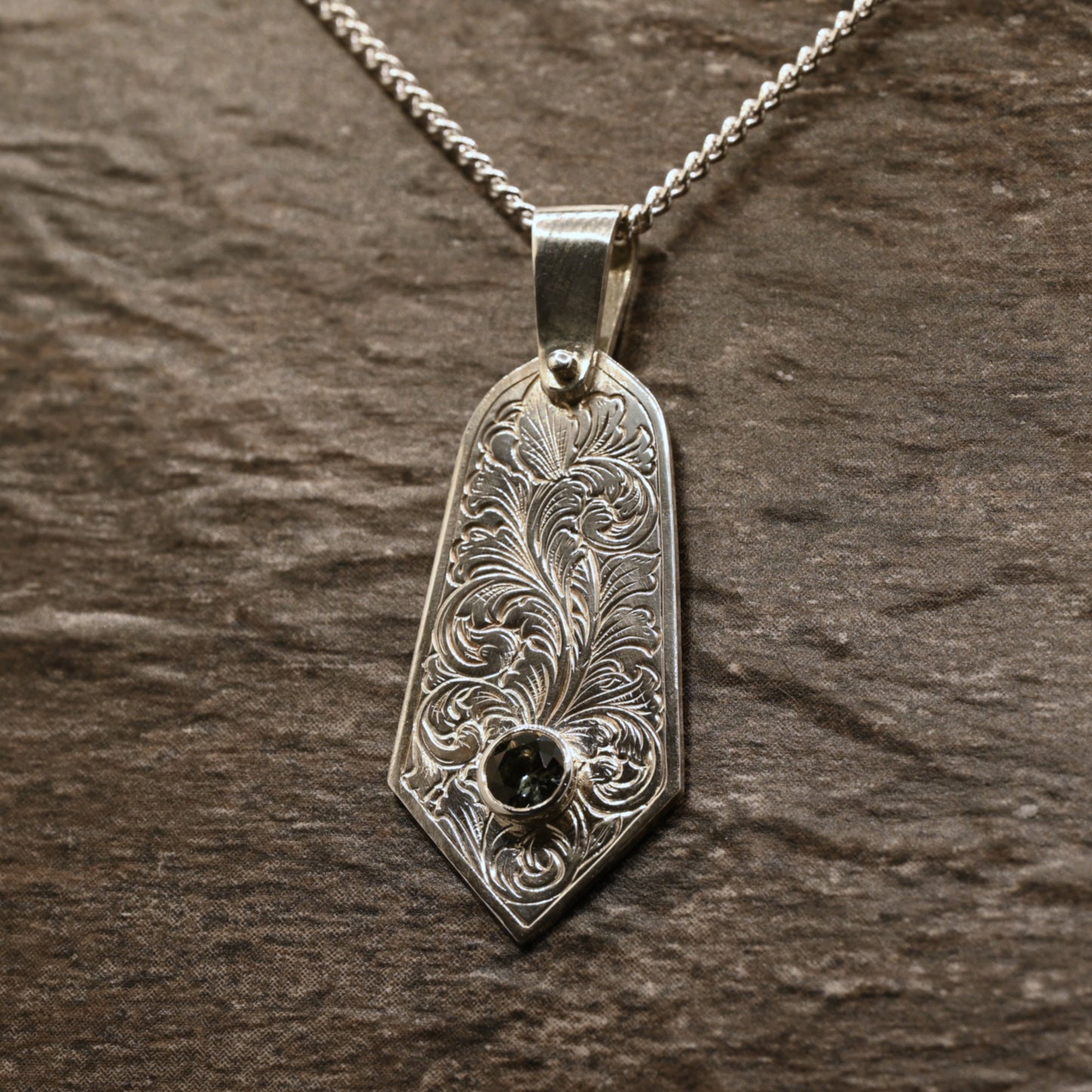 Sterling silver pendant with hand‑engraved acanthus leaf motif and green tourmaline setting