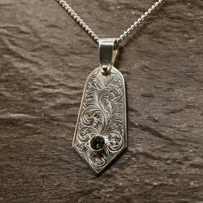 Sterling silver pendant with hand‑engraved acanthus leaf motif and green tourmaline setting