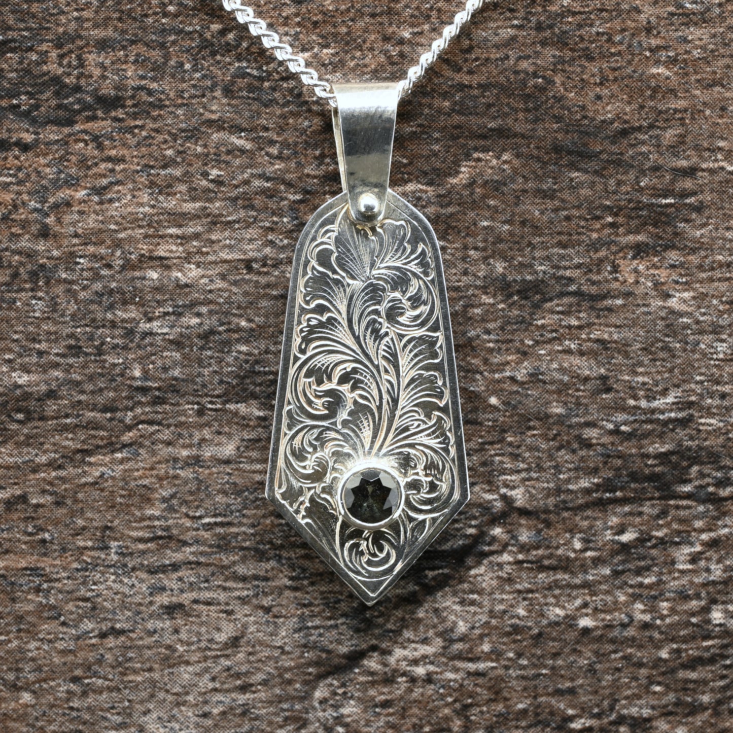 Sterling silver pendant with hand‑engraved acanthus leaf motif and green tourmaline setting