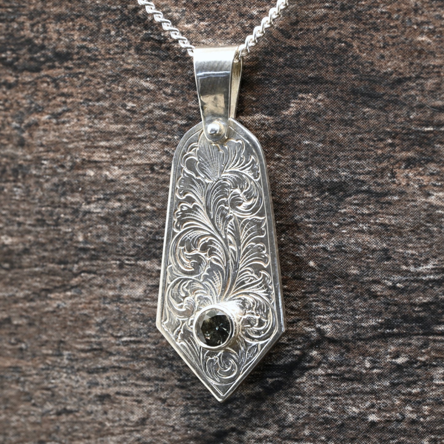 Sterling silver pendant with hand‑engraved acanthus leaf motif and green tourmaline setting