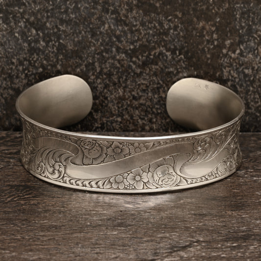 Sterling silver cuff bracelet with intricate hand‑engraved scrollwork and floral design