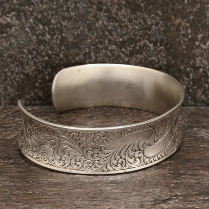 Sterling silver cuff bracelet with intricate hand‑engraved scrollwork and floral design