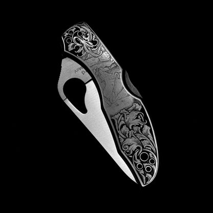 Hand-engraved Spyderco knife in closed position with detailed horse scene and relieved acanthus vine.