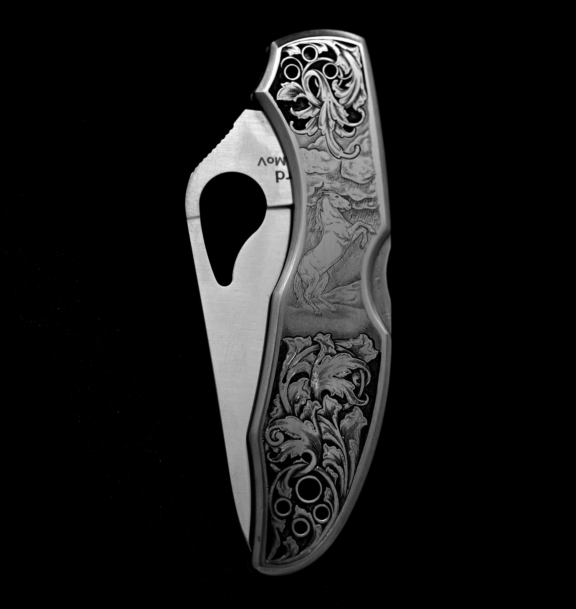Hand-engraved Spyderco knife in closed position with detailed horse scene and relieved acanthus vine.