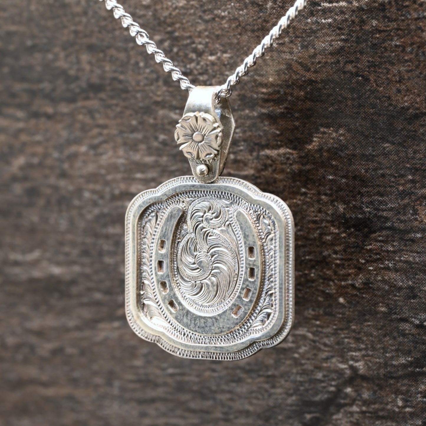 Sterling silver pendant with hand‑engraved horseshoe, scrollwork, and floral details