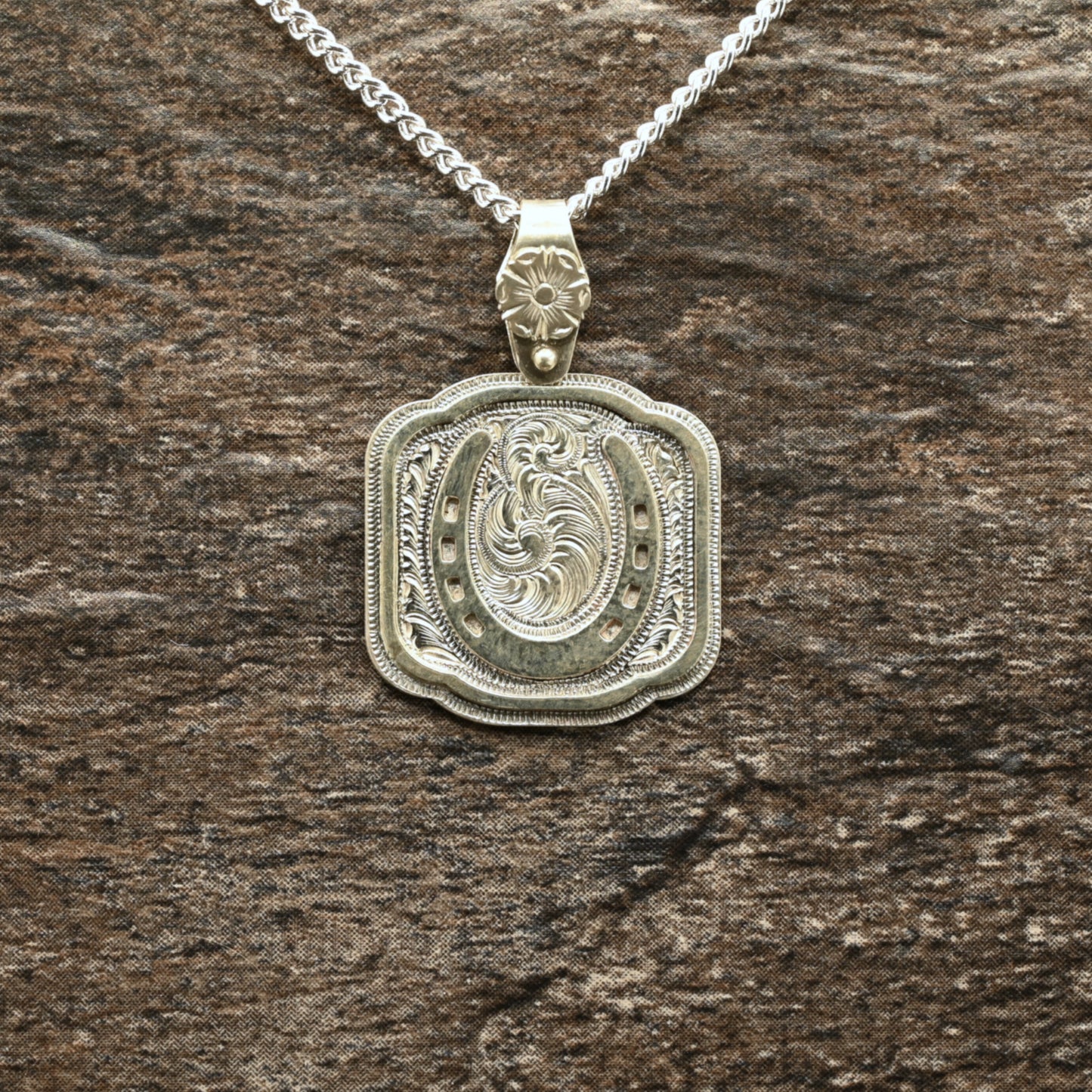 Sterling silver pendant with hand‑engraved horseshoe, scrollwork, and floral details