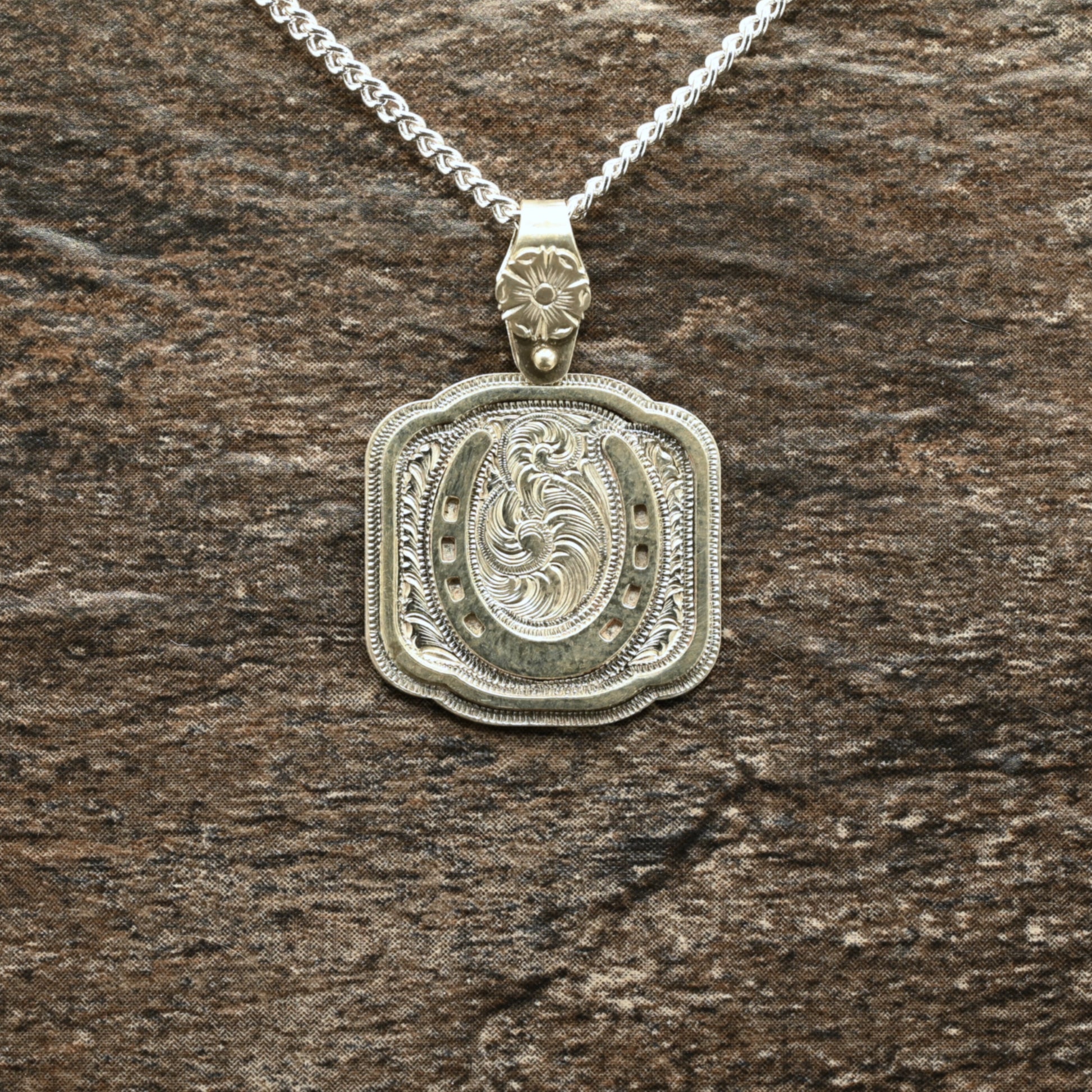 Sterling silver pendant with hand‑engraved horseshoe, scrollwork, and floral details