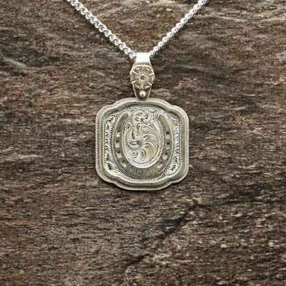 Sterling silver pendant with hand‑engraved horseshoe, scrollwork, and floral details