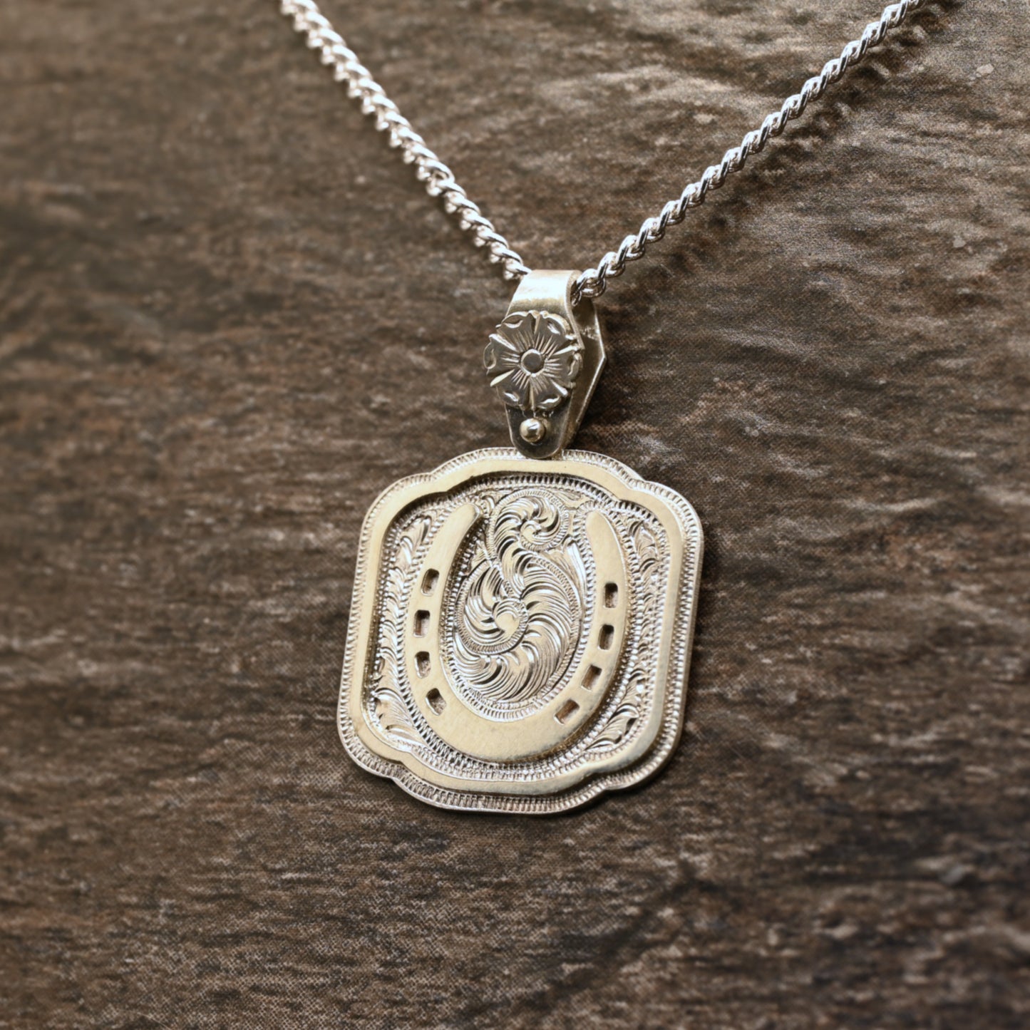 Sterling silver pendant with hand‑engraved horseshoe, scrollwork, and floral details