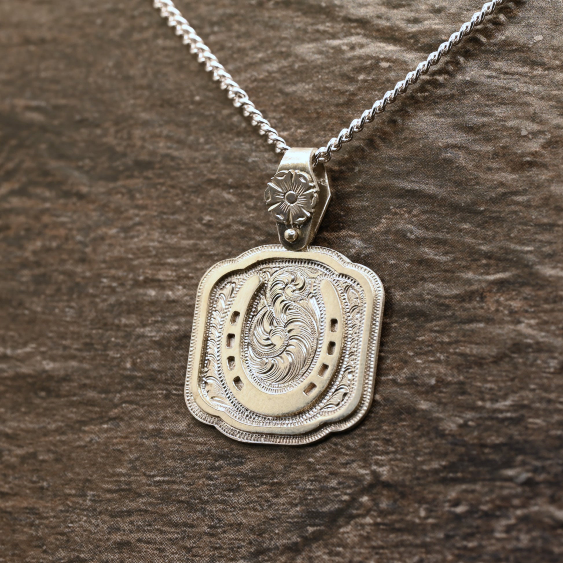 Sterling silver pendant with hand‑engraved horseshoe, scrollwork, and floral details