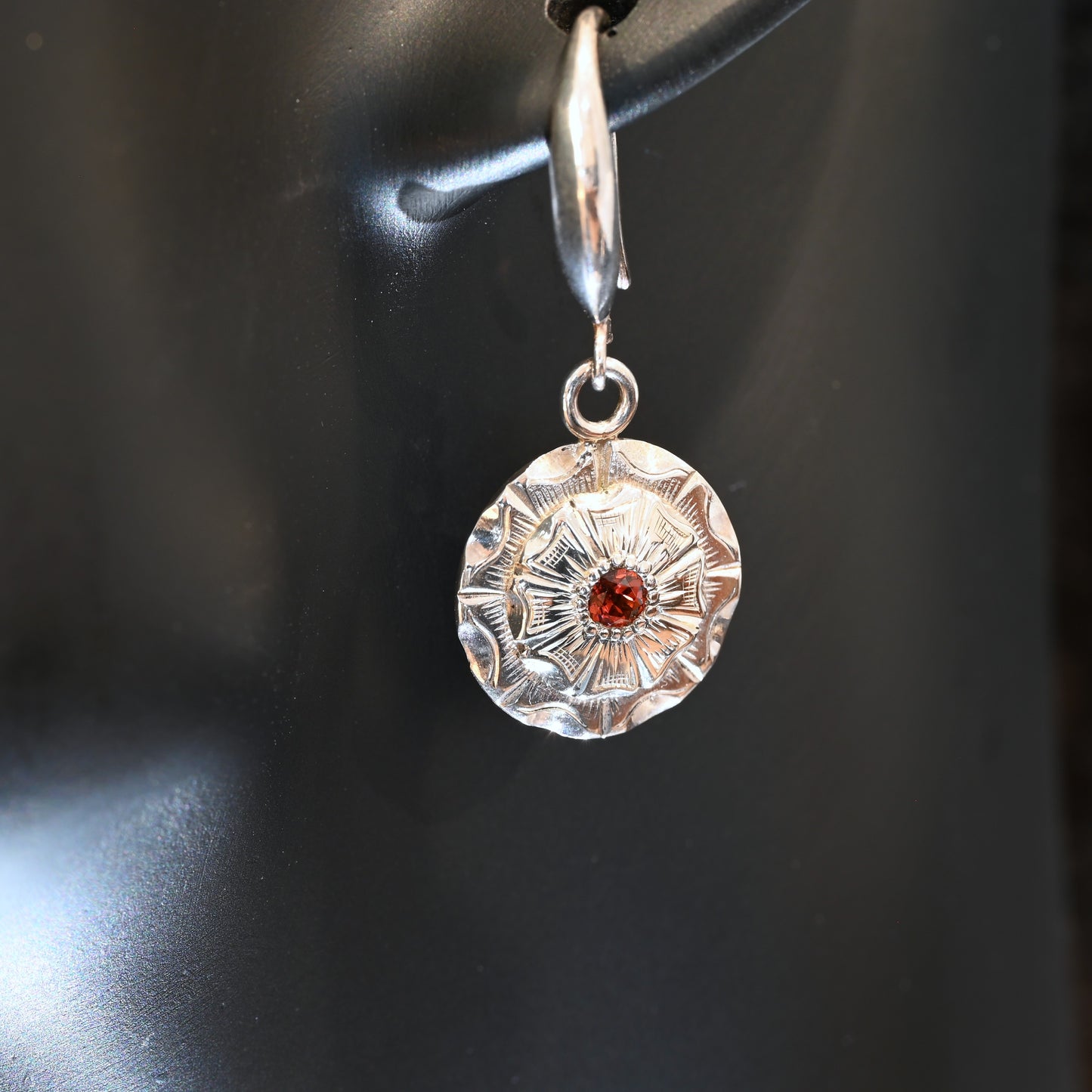 Hand‑engraved sterling silver dangle earrings with wildflower design and red centre stone
