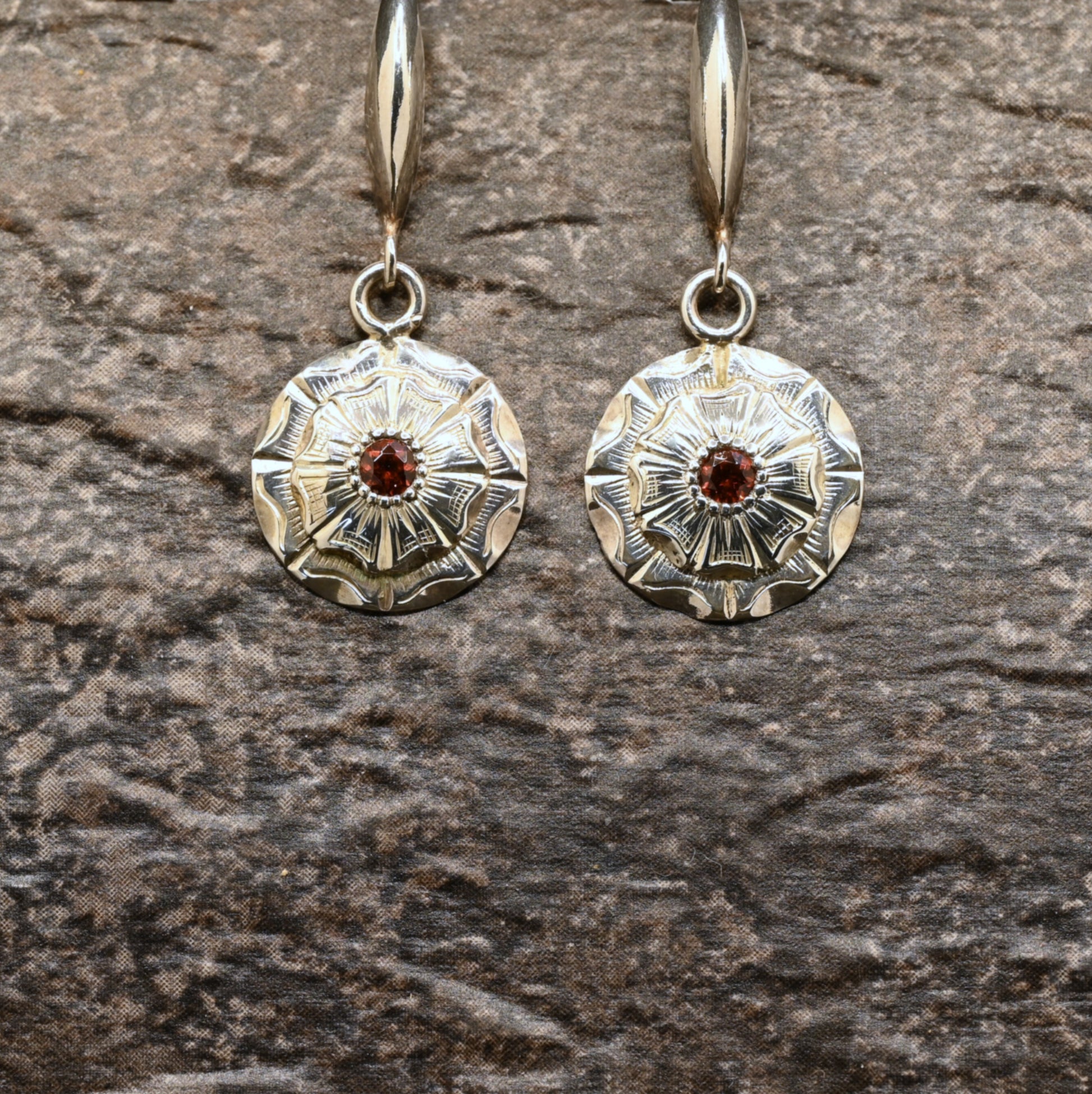 Hand‑engraved sterling silver dangle earrings with wildflower design and red centre stone