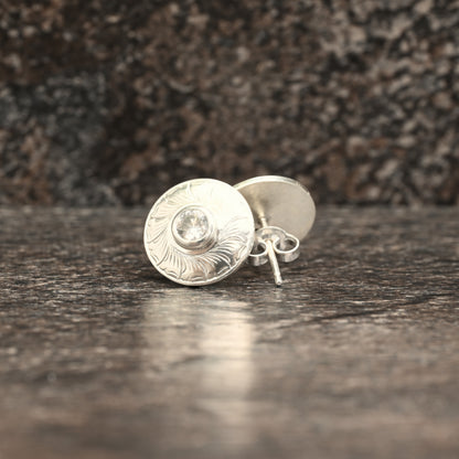 Sterling silver stud earrings with hand‑engraved leaf motif and white sapphire centre