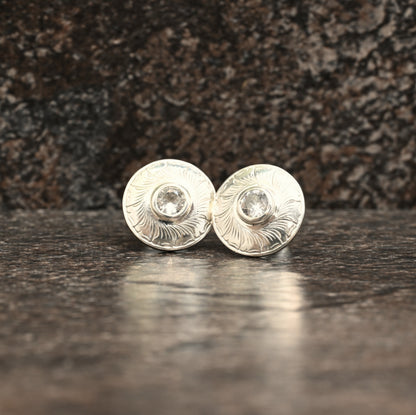 Sterling silver stud earrings with hand‑engraved leaf motif and white sapphire centre